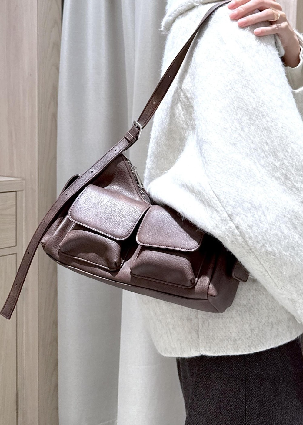 ブラウン系のショルダーバッグ、ブラック系のブーツ、ホワイト系のブルゾンを着用したレディースの秋コーディネートの10枚目の写真