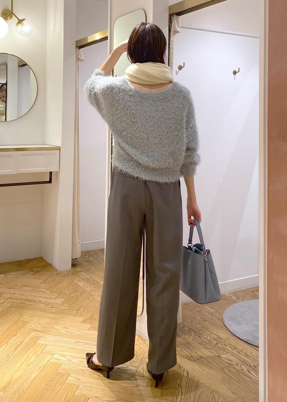 グレー系のスラックス、ブルー系のショルダーバッグ、ブラック系のパンプスを着用したレディースの冬コーディネートの3枚目の写真