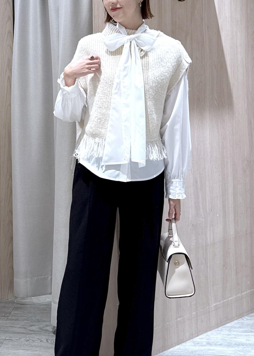 ブラック系のスラックス、ホワイト系のベスト、ホワイト系のシャツ/ブラウスを着用したレディースの秋コーディネートの7枚目の写真