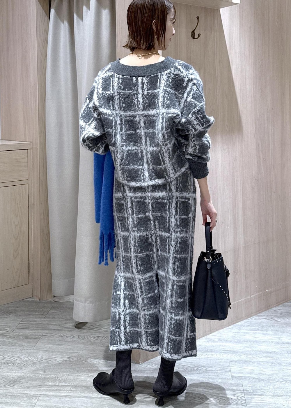 グレー系のスカート、グレー系のカーディガン/ボレロ、ブラック系のショルダーバッグを着用したレディースの冬コーディネートの2枚目の写真