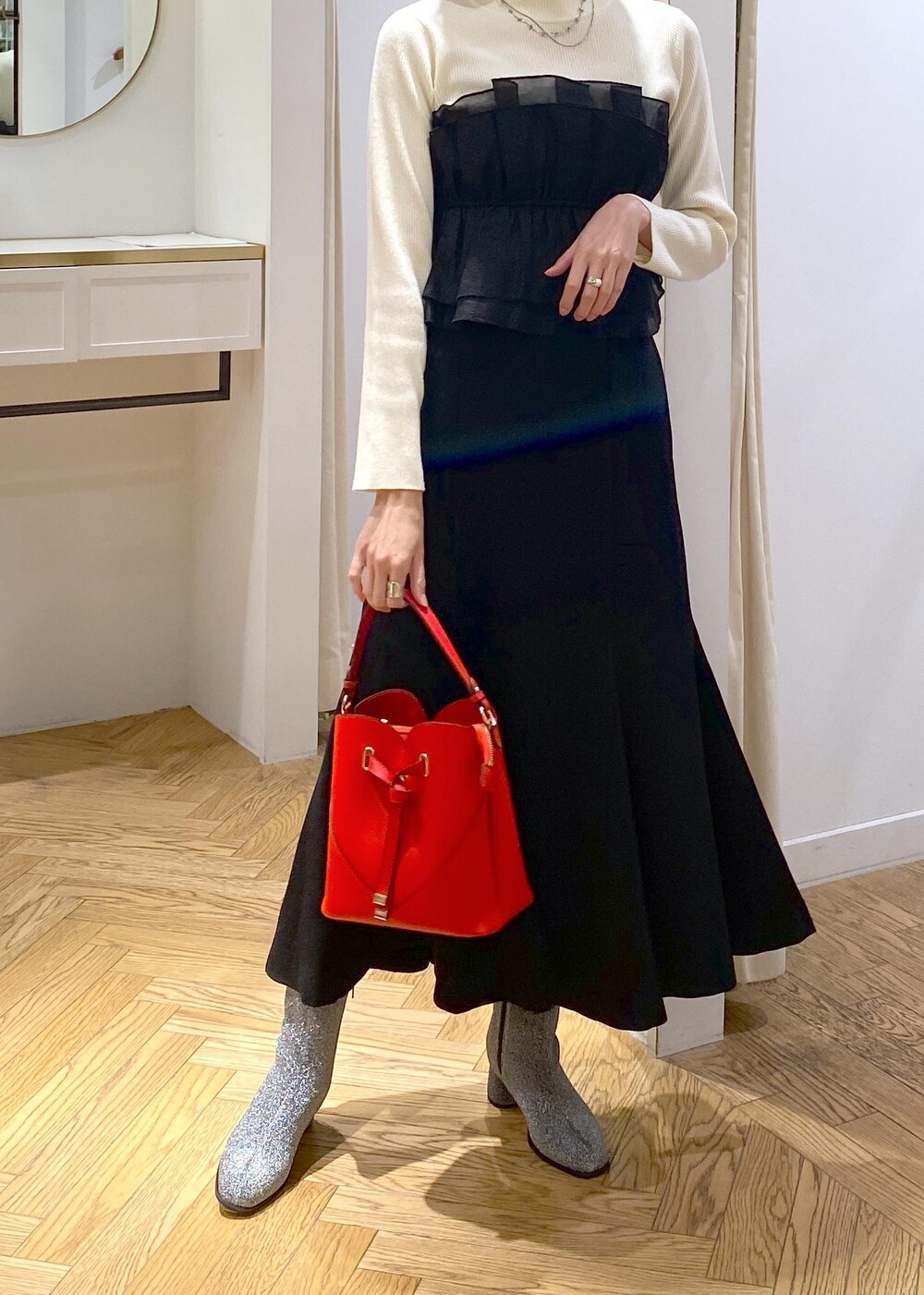 シルバー系のブーツ、ブラック系のスカート、ホワイト系のニット/セーターを着用したレディースの冬コーディネートの3枚目の写真