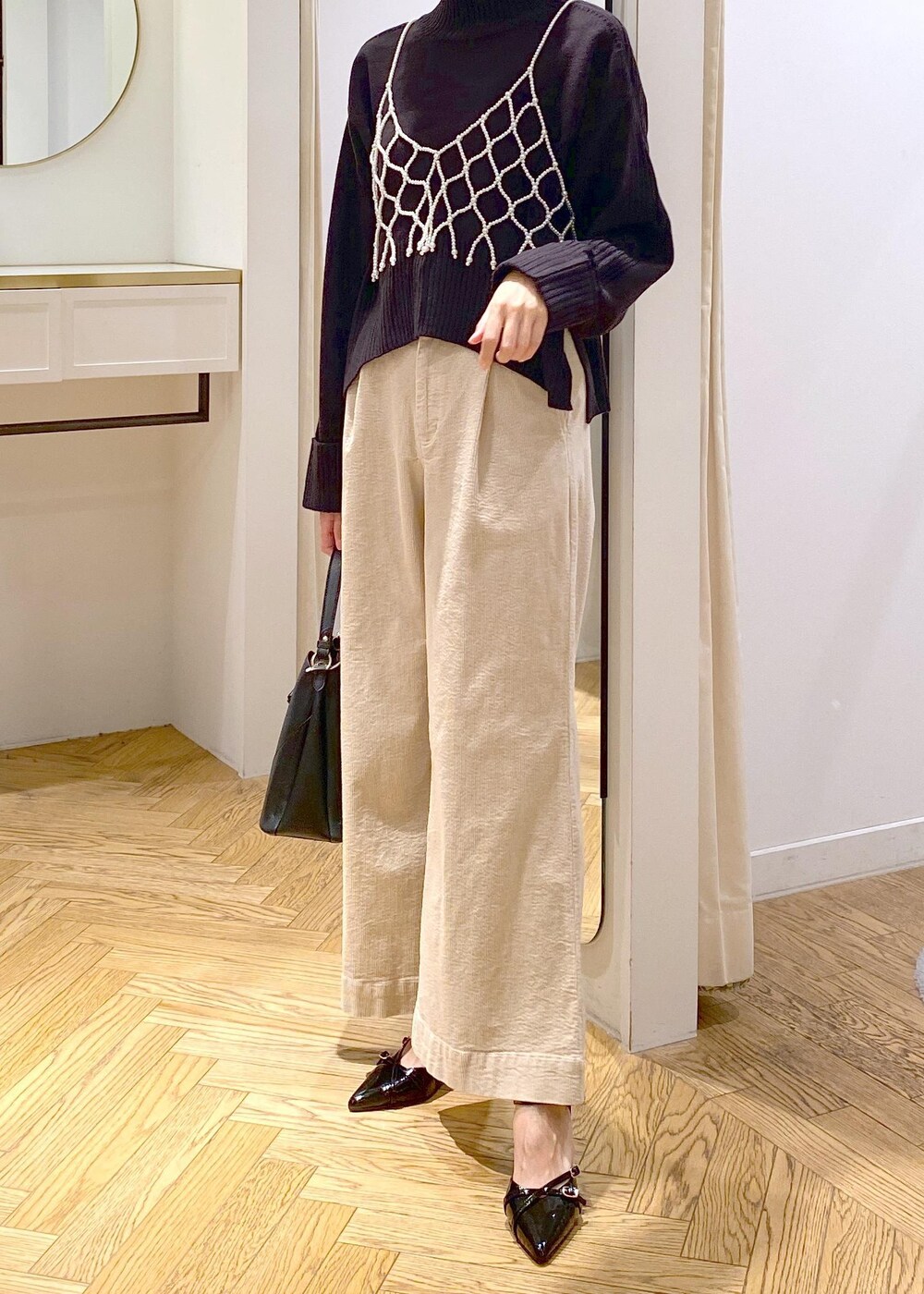 ブラック系のショルダーバッグ、ホワイト系のキャミソール、ベージュ系のスラックスを着用したレディースの秋コーディネートの4枚目の写真