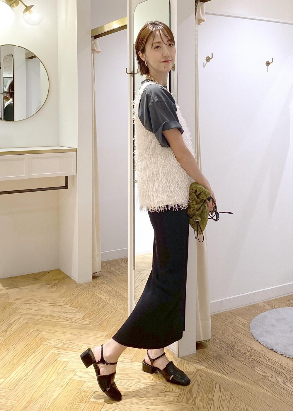 ブラック系のサンダル、ホワイト系のタンクトップ、ゴールド系のショルダーバッグを着用したレディースの夏コーディネートの2枚目の写真