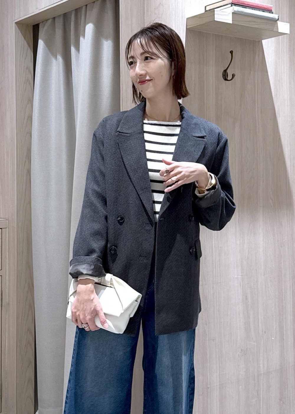 ブルー系のデニムパンツ、グレー系のテーラードジャケット、ホワイト系のショルダーバッグを着用したレディースの冬コーディネートの6枚目の写真