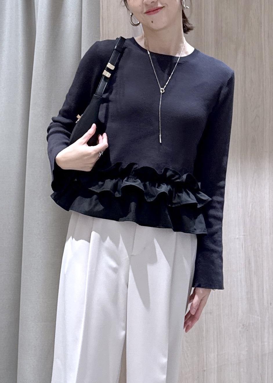 ブラック系のショルダーバッグ、ブラック系のパンプス、グレー系のニット/セーターを着用したレディースの春コーディネートの4枚目の写真