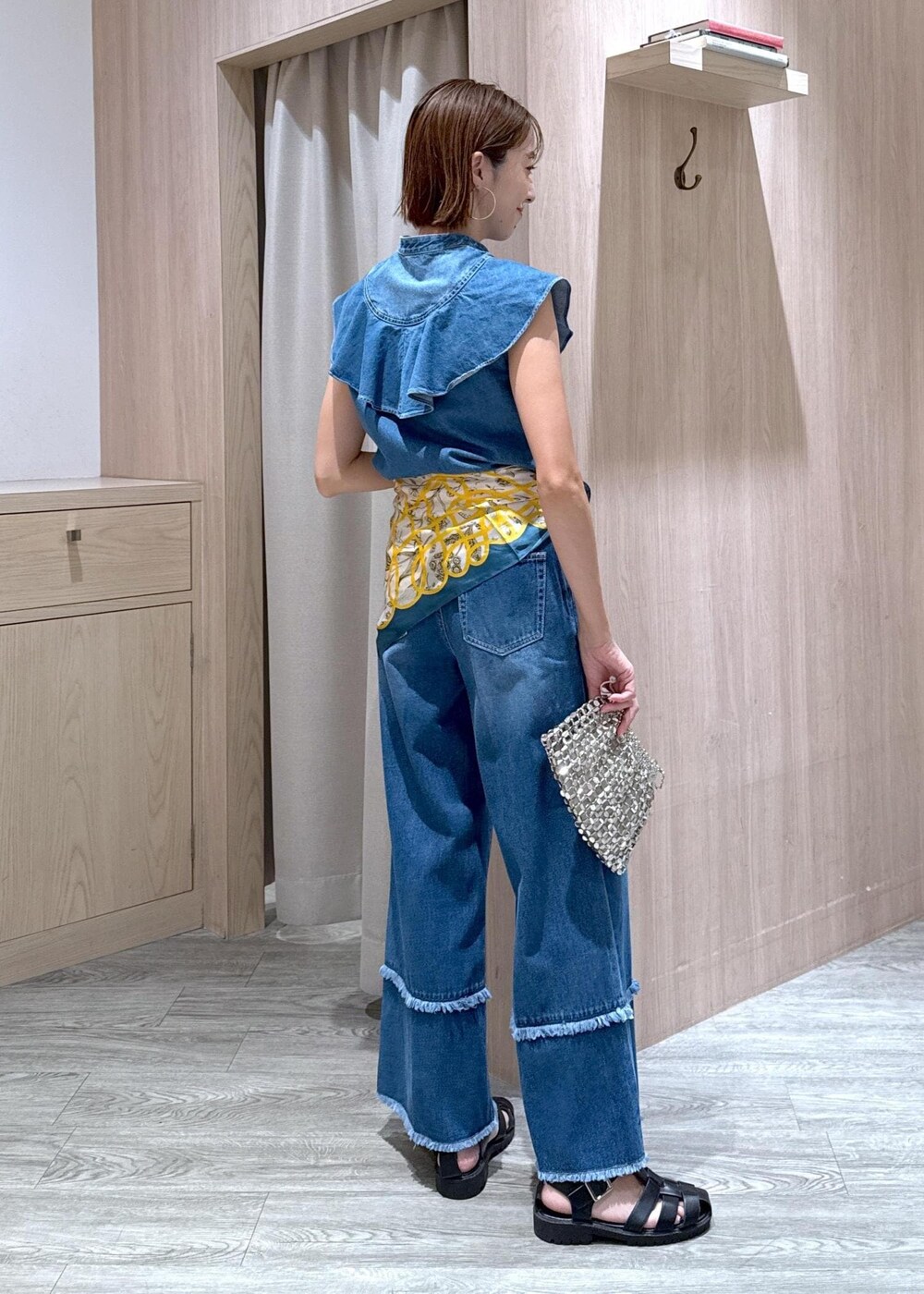 シルバー系のハンドバッグ、ブルー系のシャツ/ブラウス、ブルー系のデニムパンツを着用したレディースの夏コーディネートの3枚目の写真