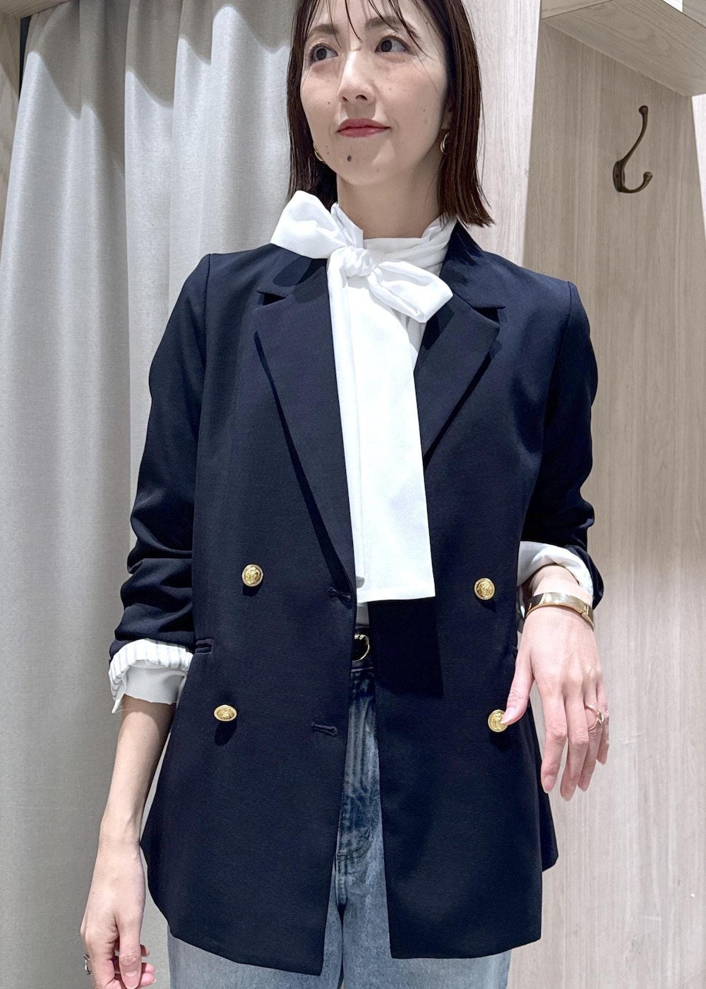 ブルー系のテーラードジャケット、ブラック系のショルダーバッグ、ブルー系のデニムパンツを着用したレディースの冬コーディネートの4枚目の写真