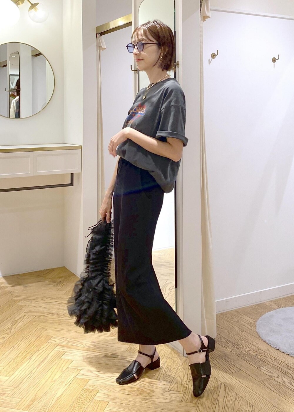 ブラック系のショルダーバッグ、ブラック系のスカート、グレー系のTシャツ/カットソーを着用したレディースの夏コーディネートの4枚目の写真