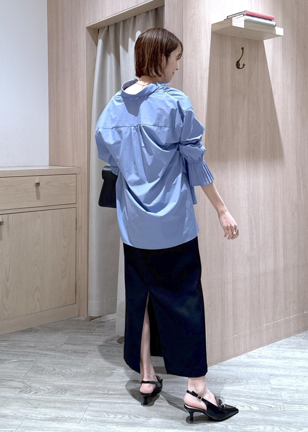 ブラック系のハンドバッグ、ブルー系のシャツ/ブラウス、ブラック系のパンプスを着用したレディースの春コーディネートの3枚目の写真
