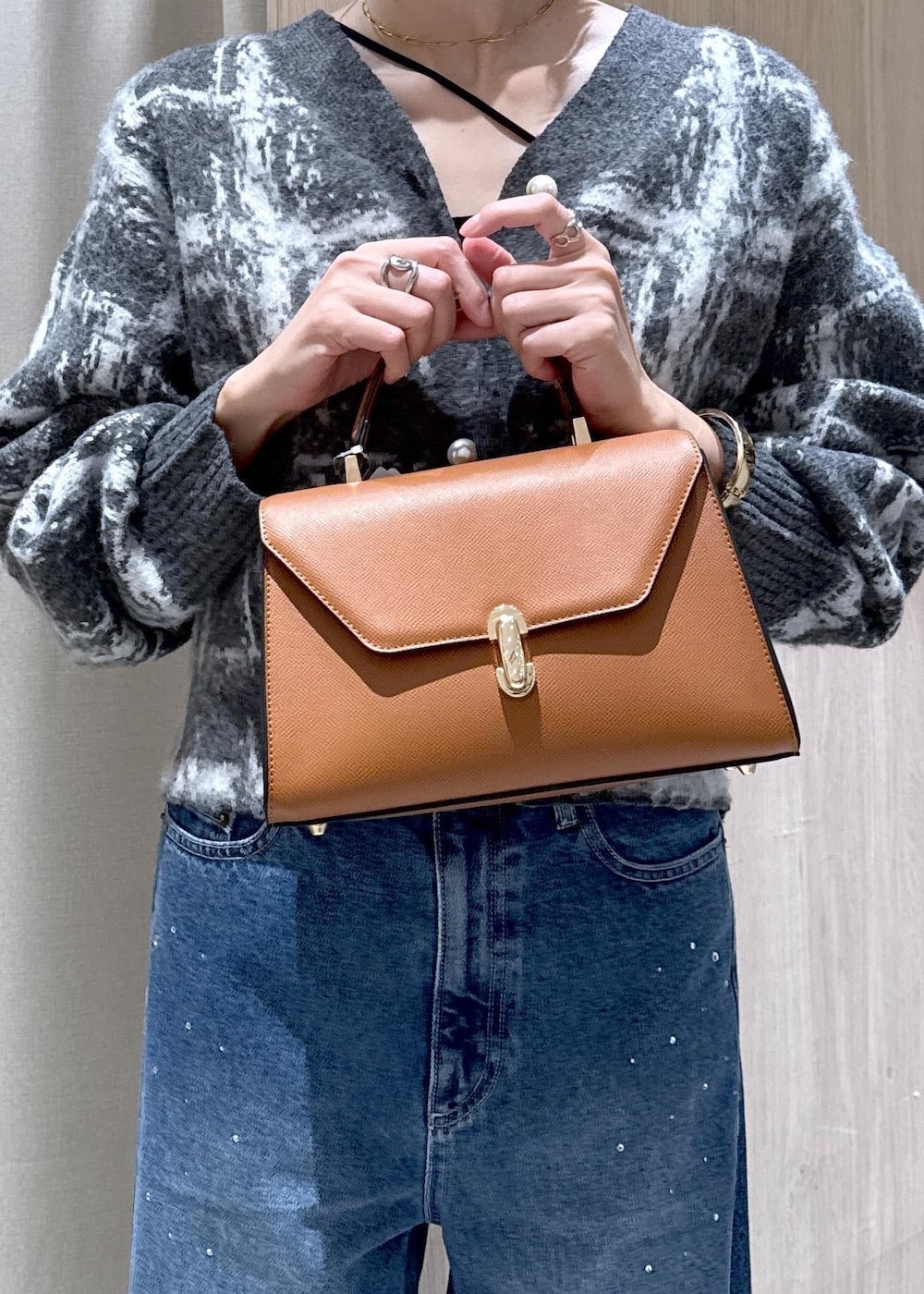 ブルー系のデニムパンツ、イエロー系のハンドバッグ、グレー系のカーディガン/ボレロを着用したレディースの冬コーディネートの8枚目の写真