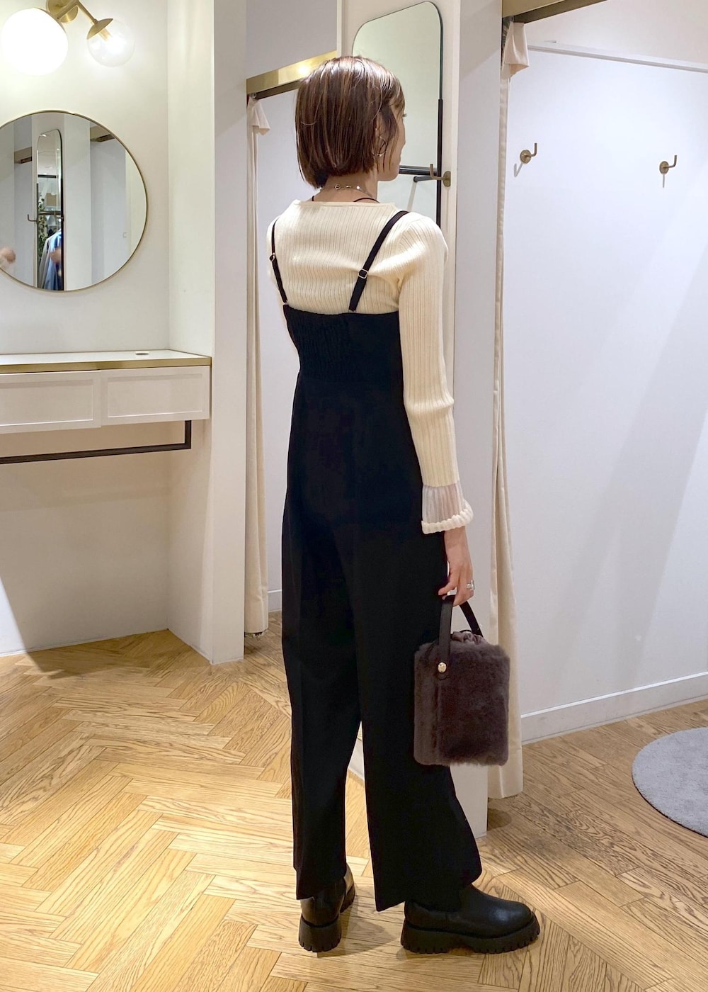 グレー系のショルダーバッグ、ブラック系のサロペット/オーバーオール、ホワイト系のニット/セーターを着用したレディースの冬コーディネートの4枚目の写真