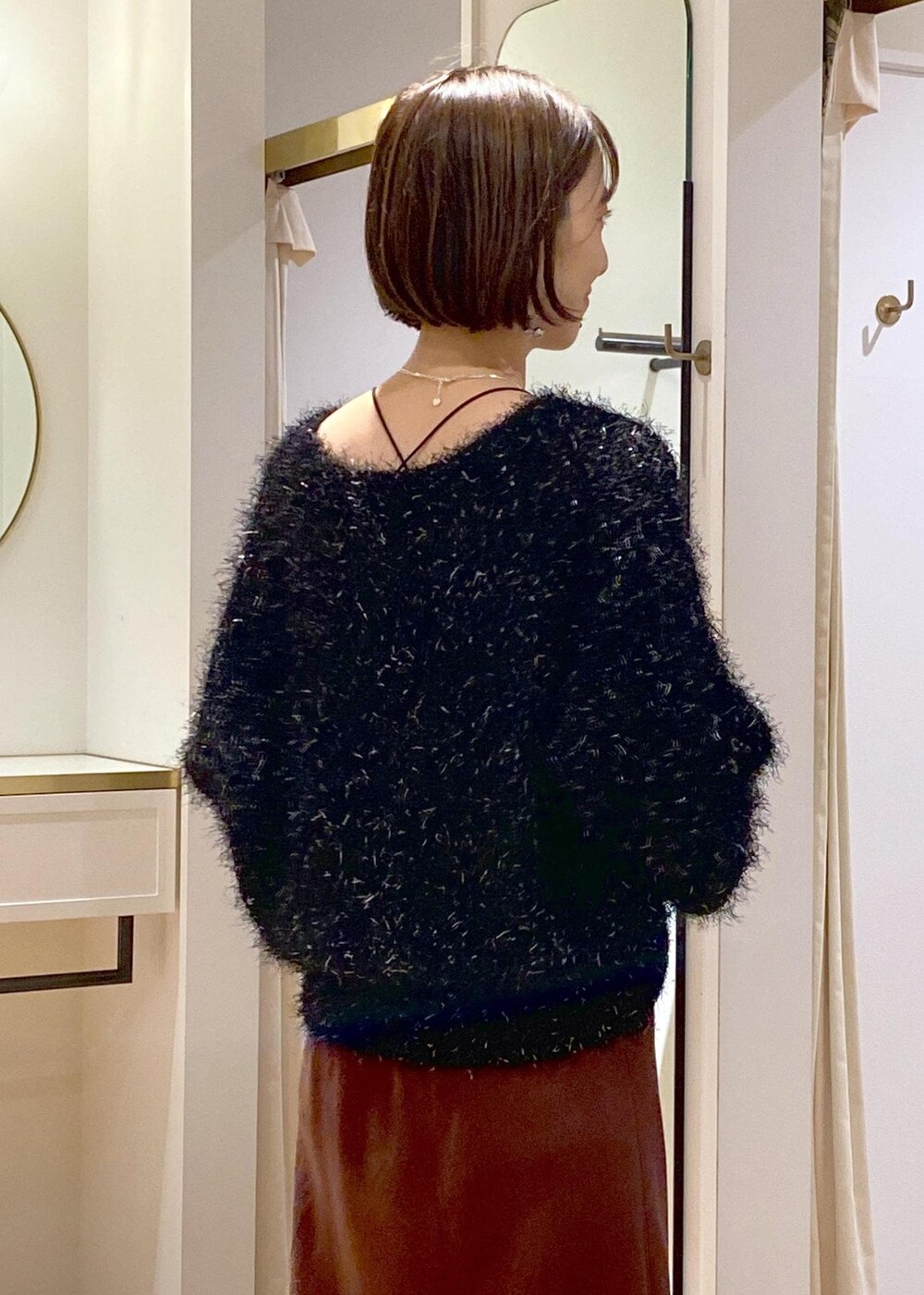 ホワイト系のブーツ、ブラック系のハンドバッグ、ブラック系のニット/セーターを着用したレディースの冬コーディネートの7枚目の写真