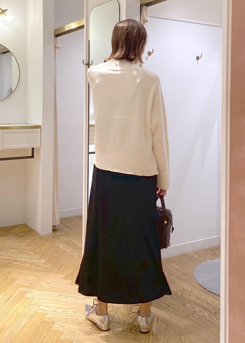 ブラック系のスカート、ホワイト系のニット/セーター、グレー系のショルダーバッグを着用したレディースの秋コーディネートの3枚目の写真
