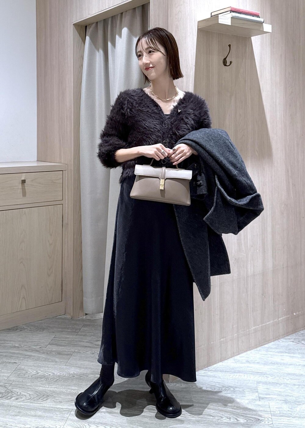 ベージュ系のショルダーバッグ、グレー系のその他アウター、ブラック系のスカートを着用したレディースの冬コーディネートの6枚目の写真