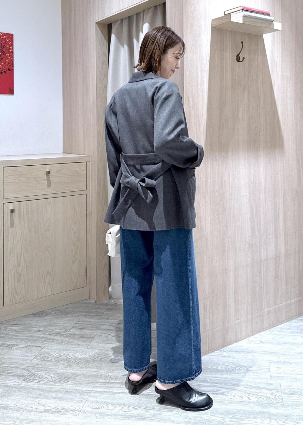 ブルー系のデニムパンツ、グレー系のテーラードジャケット、ホワイト系のショルダーバッグを着用したレディースの冬コーディネートの2枚目の写真