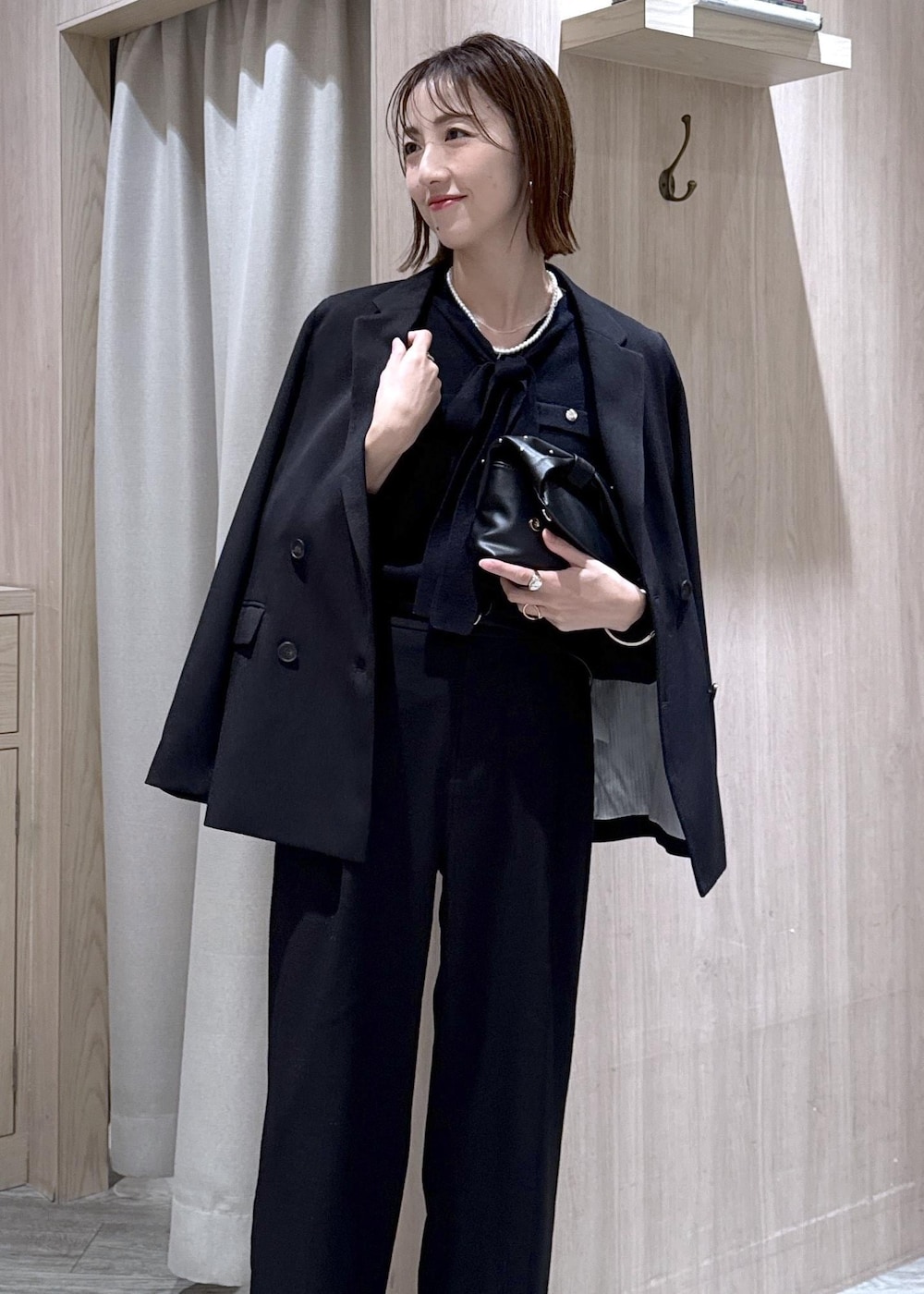 ブラック系のスラックス、ブラック系のテーラードジャケット、ブラック系のショルダーバッグを着用したレディースの冬コーディネートの3枚目の写真
