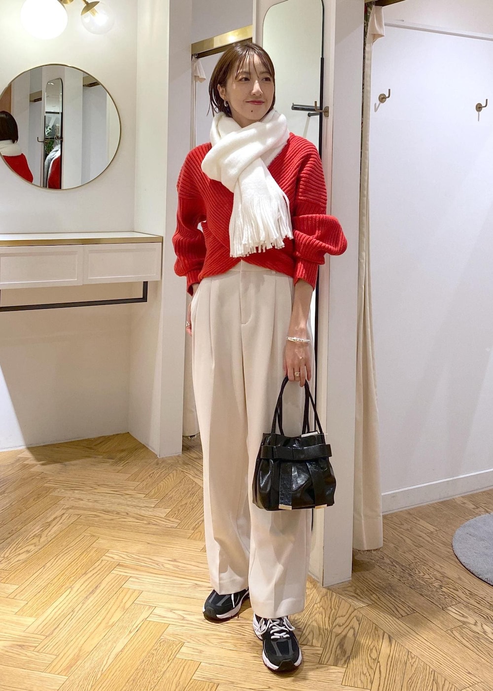 レッド系のニット/セーター、ホワイト系のスラックス、ブラック系のショルダーバッグを着用したレディースの冬コーディネートの2枚目の写真
