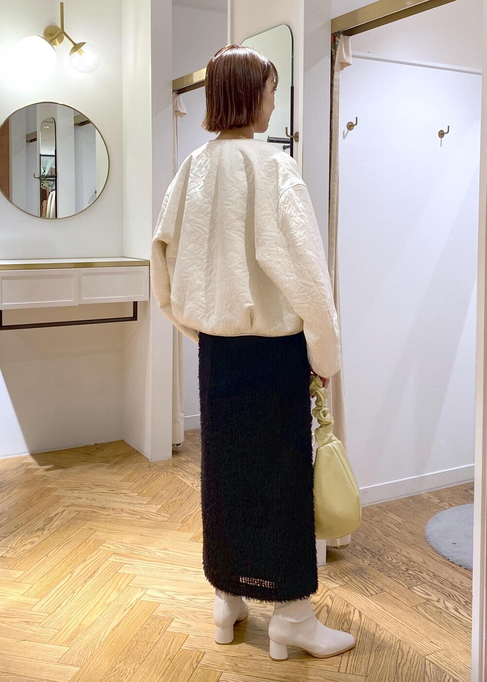 ホワイト系のブーツ、ブラック系のスカート、ホワイト系のブルゾンを着用したレディースの秋コーディネートの3枚目の写真