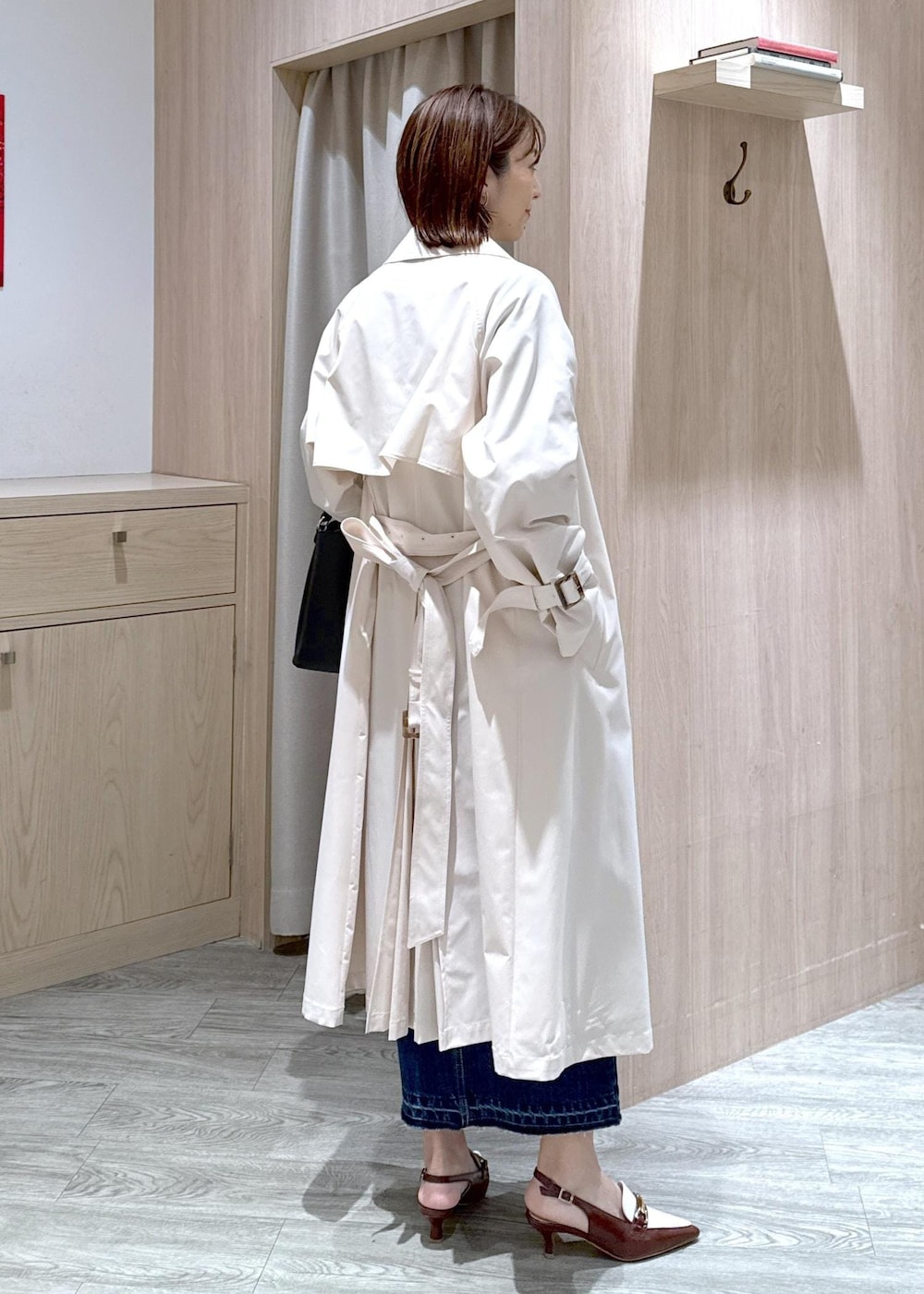 ブラック系のショルダーバッグ、ブラウン系のパンプス、ブルー系のデニムスカートを着用したレディースの春コーディネートの2枚目の写真