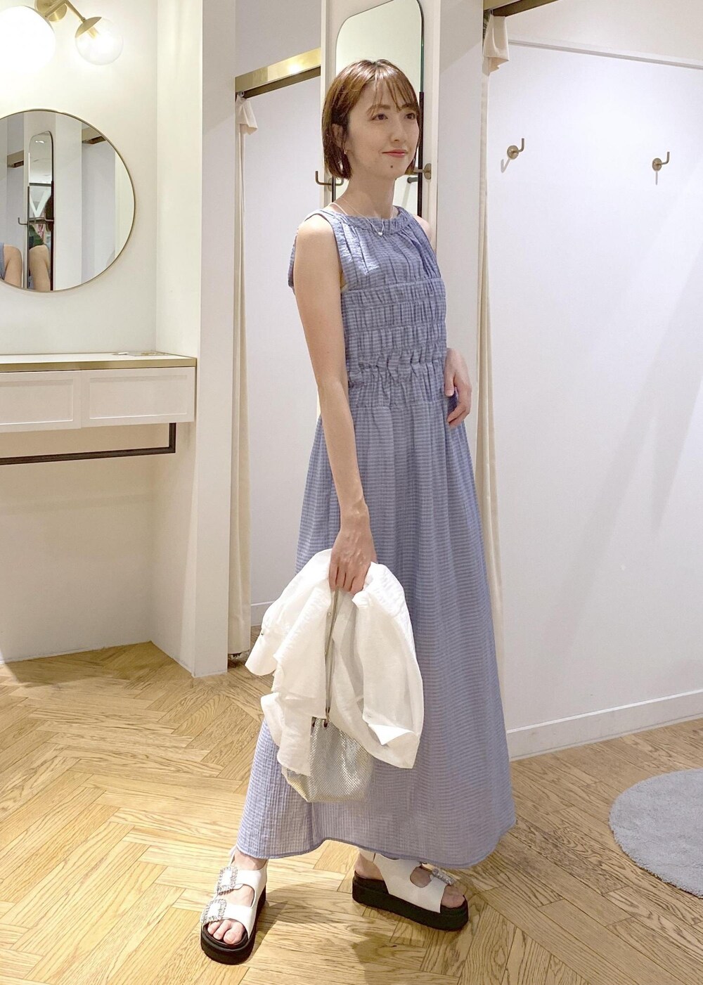 ホワイト系のサンダル、ブルー系のワンピース、シルバー系のショルダーバッグを着用したレディースの夏コーディネートの5枚目の写真