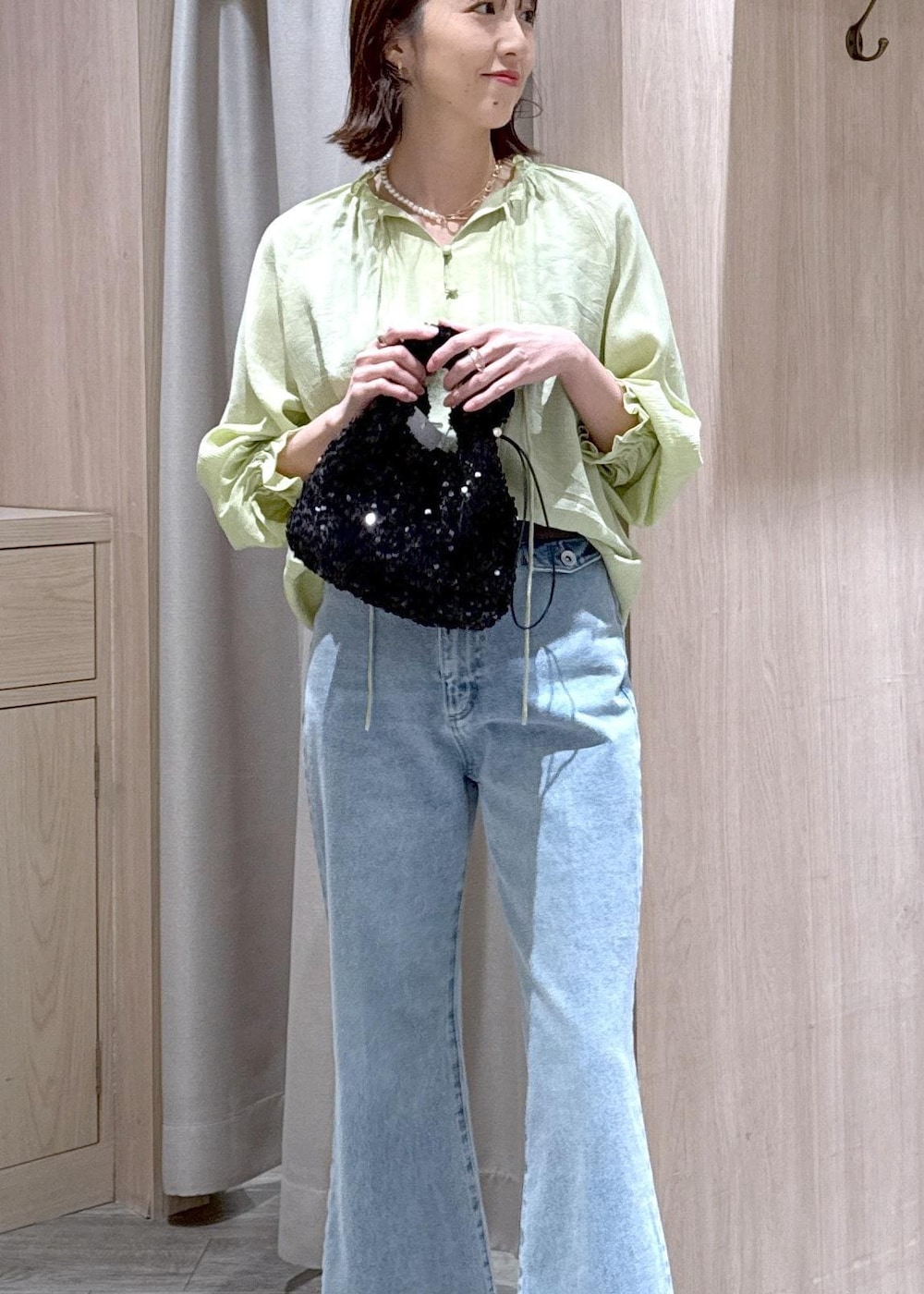 ブルー系のデニムパンツ、ブラウン系のパンプス、ブラック系のハンドバッグを着用したレディースの春コーディネートの6枚目の写真