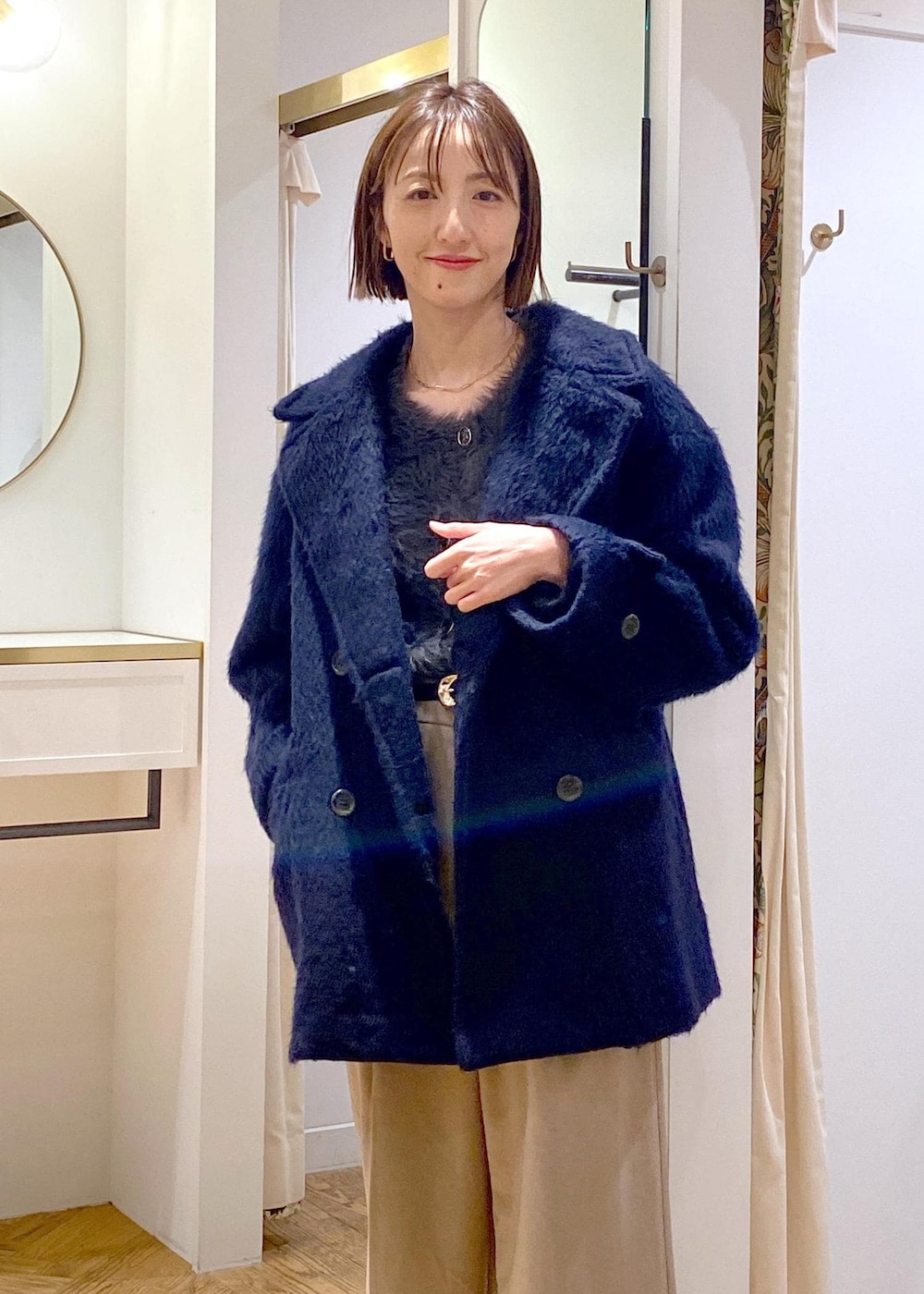 ホワイト系のショルダーバッグ、ベージュ系のスラックス、グレー系のカーディガン/ボレロを着用したレディースの冬コーディネートの5枚目の写真