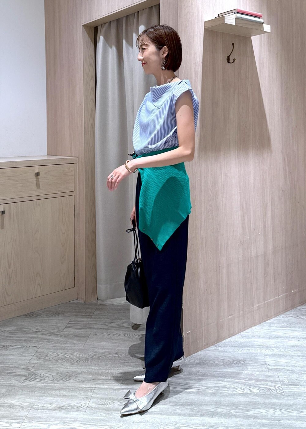 シルバー系のパンプス、ブラック系のハンドバッグ、ブルー系のスラックスを着用したレディースの夏コーディネートの4枚目の写真