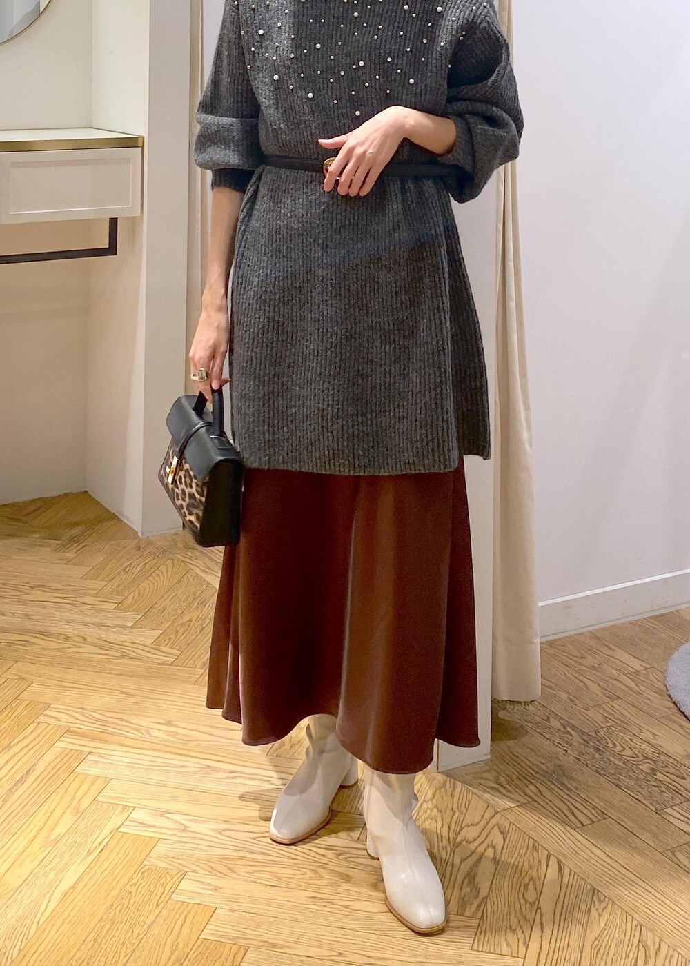 ホワイト系のブーツ、ブラウン系のスカート、グレー系のワンピースを着用したレディースの冬コーディネートの8枚目の写真