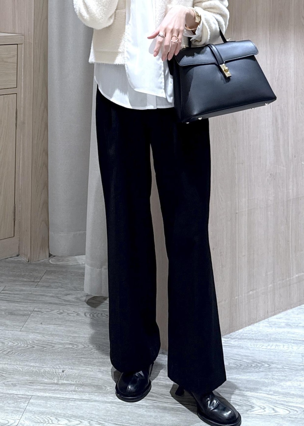 ブラック系のハンドバッグ、ブラック系のスラックス、ホワイト系のカーディガン/ボレロを着用したレディースの冬コーディネートの5枚目の写真