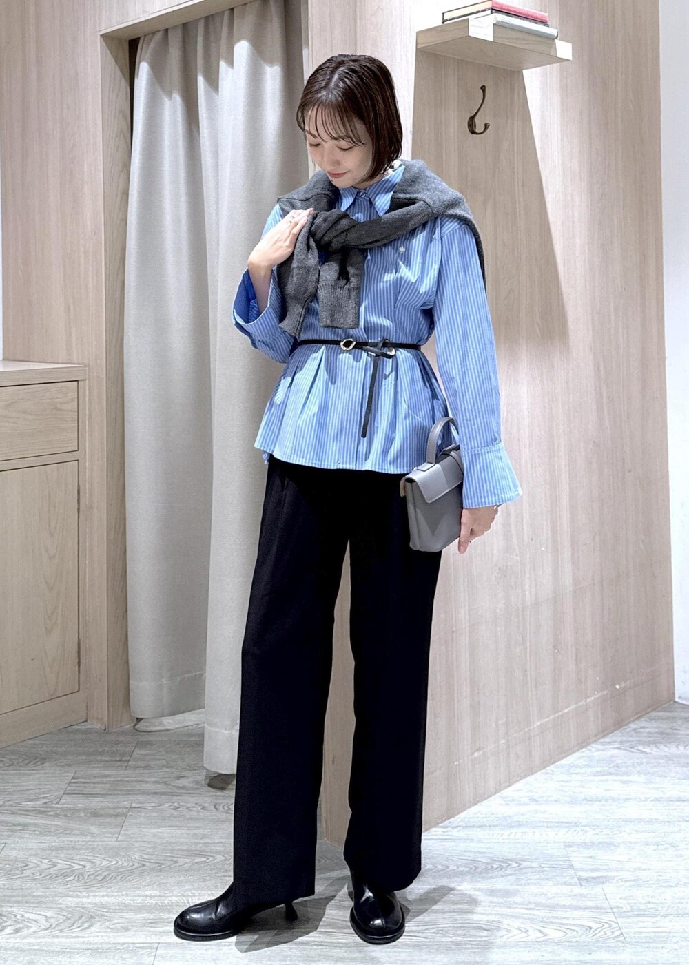 グレー系のショルダーバッグ、ブラック系のスラックス、グレー系のカーディガン/ボレロを着用したレディースの秋コーディネートの2枚目の写真