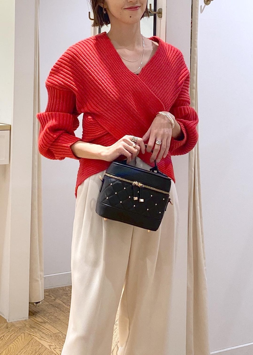 レッド系のニット/セーター、ホワイト系のスラックス、ブラック系のハンドバッグを着用したレディースの冬コーディネートの5枚目の写真