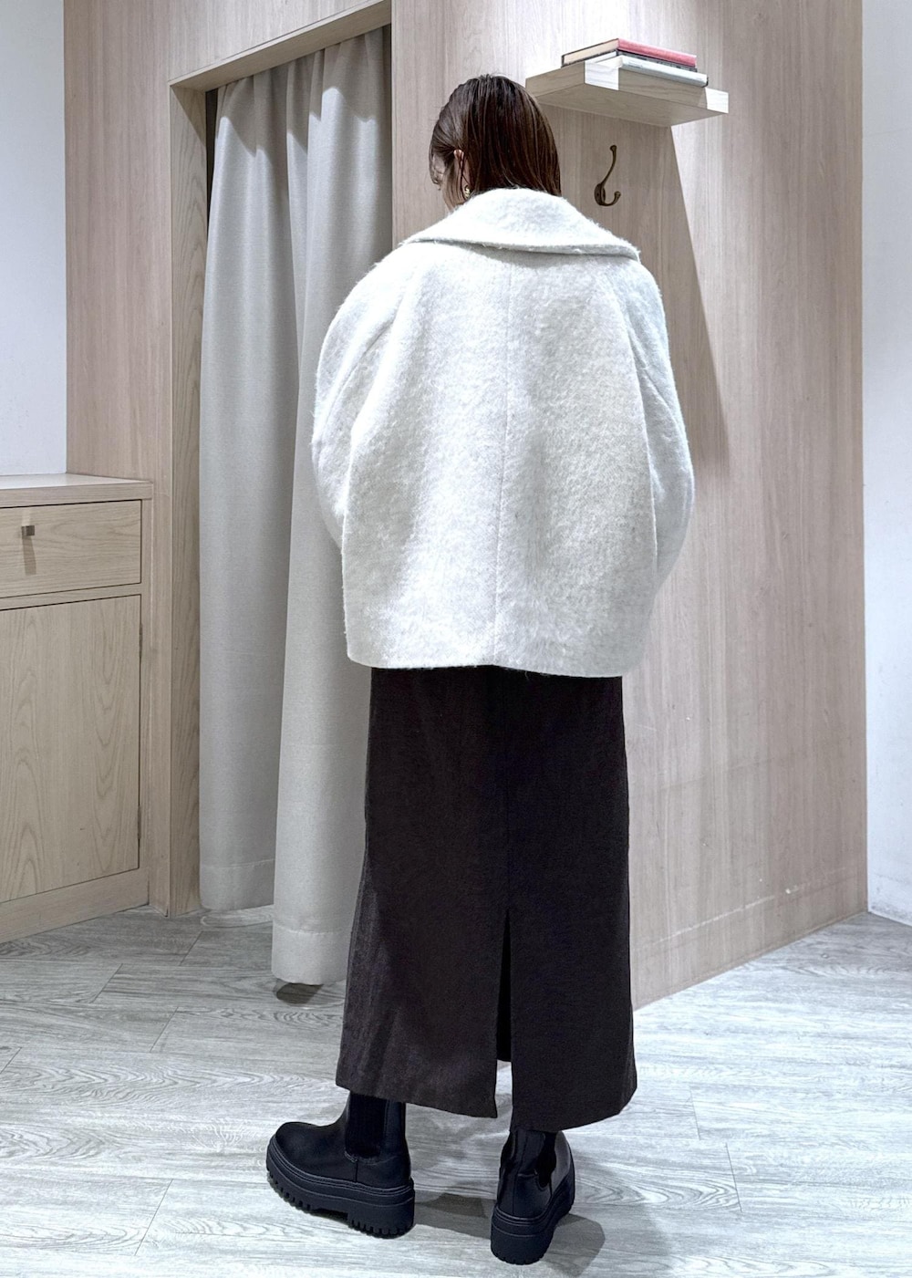 ブラウン系のショルダーバッグ、ブラック系のブーツ、ホワイト系のブルゾンを着用したレディースの秋コーディネートの4枚目の写真