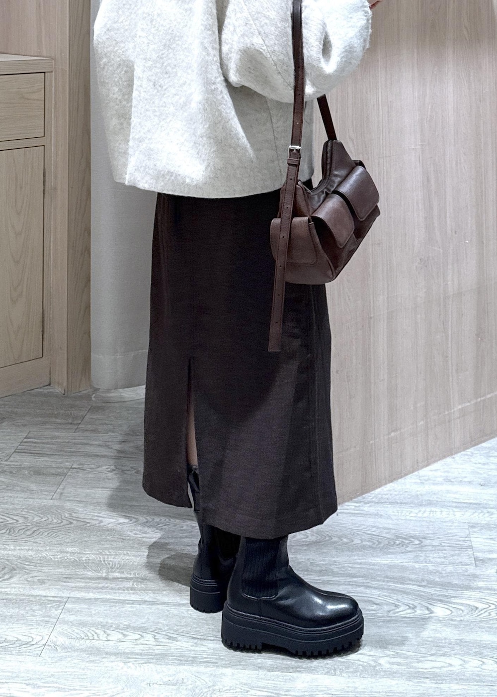 ブラウン系のショルダーバッグ、ブラック系のブーツ、ホワイト系のブルゾンを着用したレディースの秋コーディネートの5枚目の写真