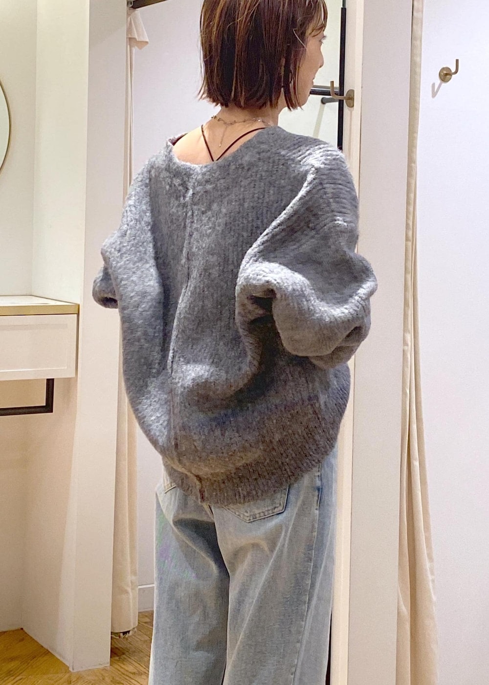 シルバー系のショルダーバッグ、ブルー系のデニムパンツ、グレー系のカーディガン/ボレロを着用したレディースの冬コーディネートの10枚目の写真