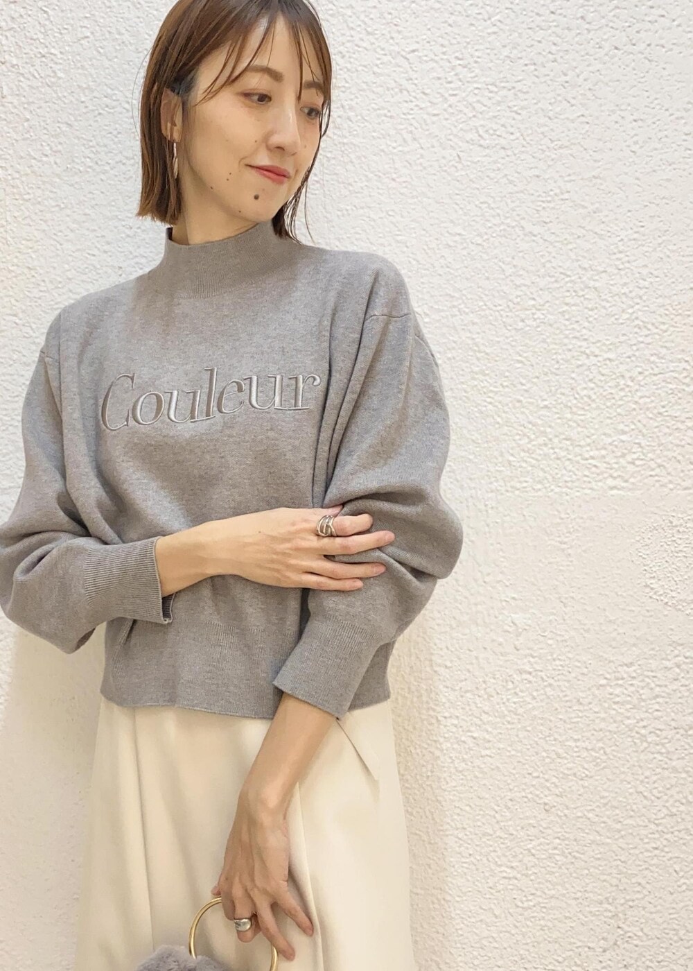 グレー系のハンドバッグ、ブラック系のブーツ、グレー系のニット/セーターを着用したレディースの冬コーディネートの4枚目の写真