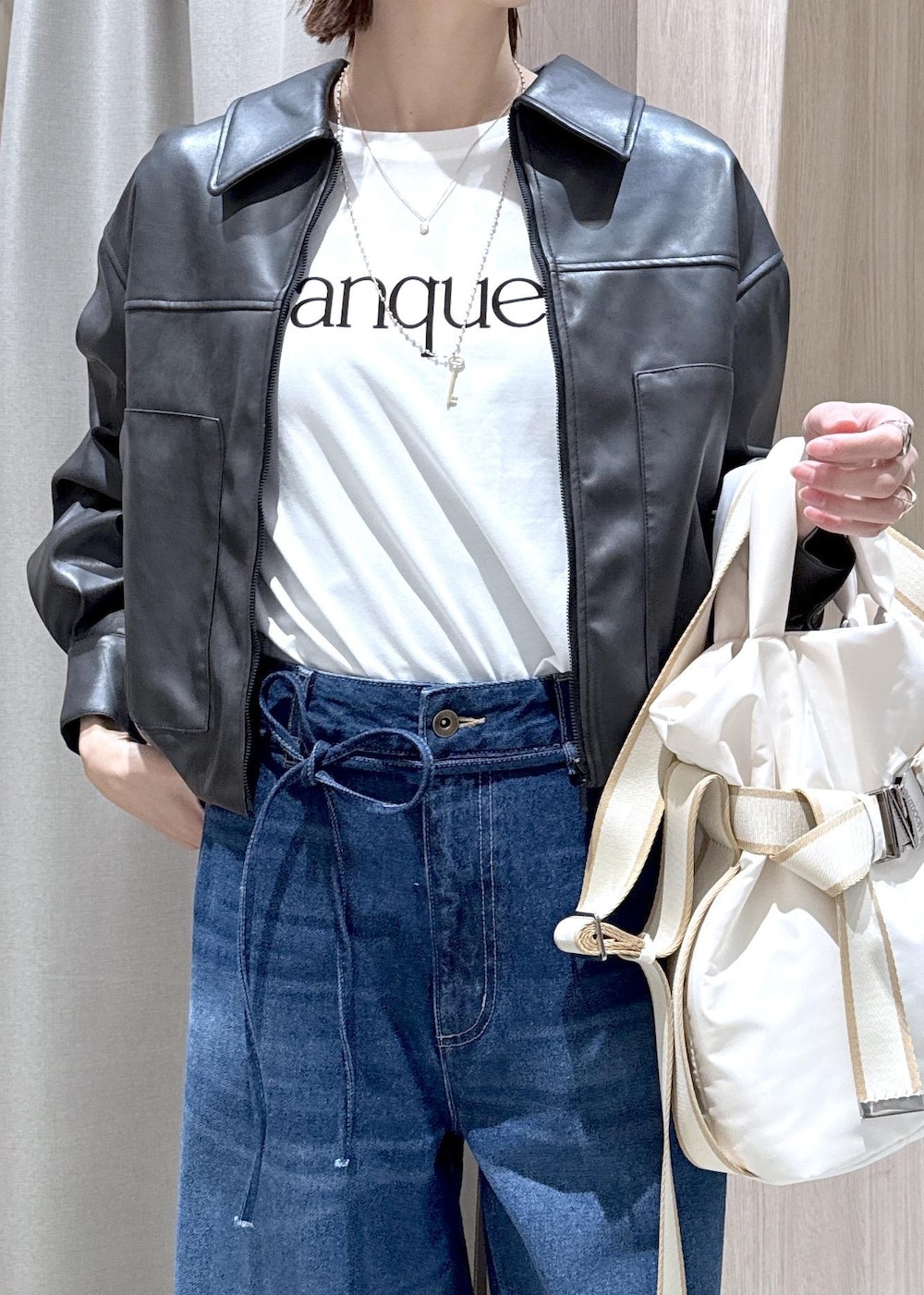 ホワイト系のトートバッグ、ブラック系のブルゾン、ホワイト系のTシャツ/カットソーを着用したレディースの冬コーディネートの9枚目の写真