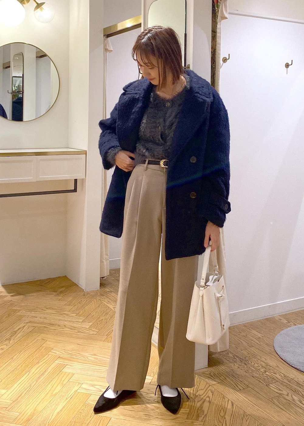 ホワイト系のショルダーバッグ、ベージュ系のスラックス、グレー系のカーディガン/ボレロを着用したレディースの冬コーディネートの4枚目の写真