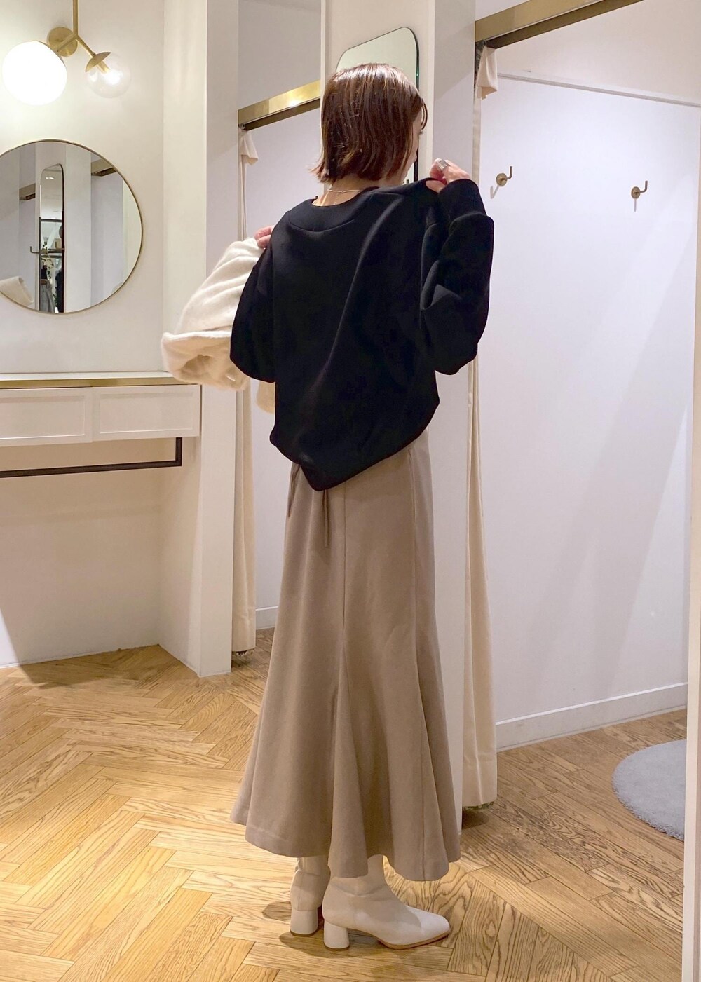 ホワイト系のブーツ、ベージュ系のスカート、ホワイト系のその他アウターを着用したレディースの秋コーディネートの10枚目の写真