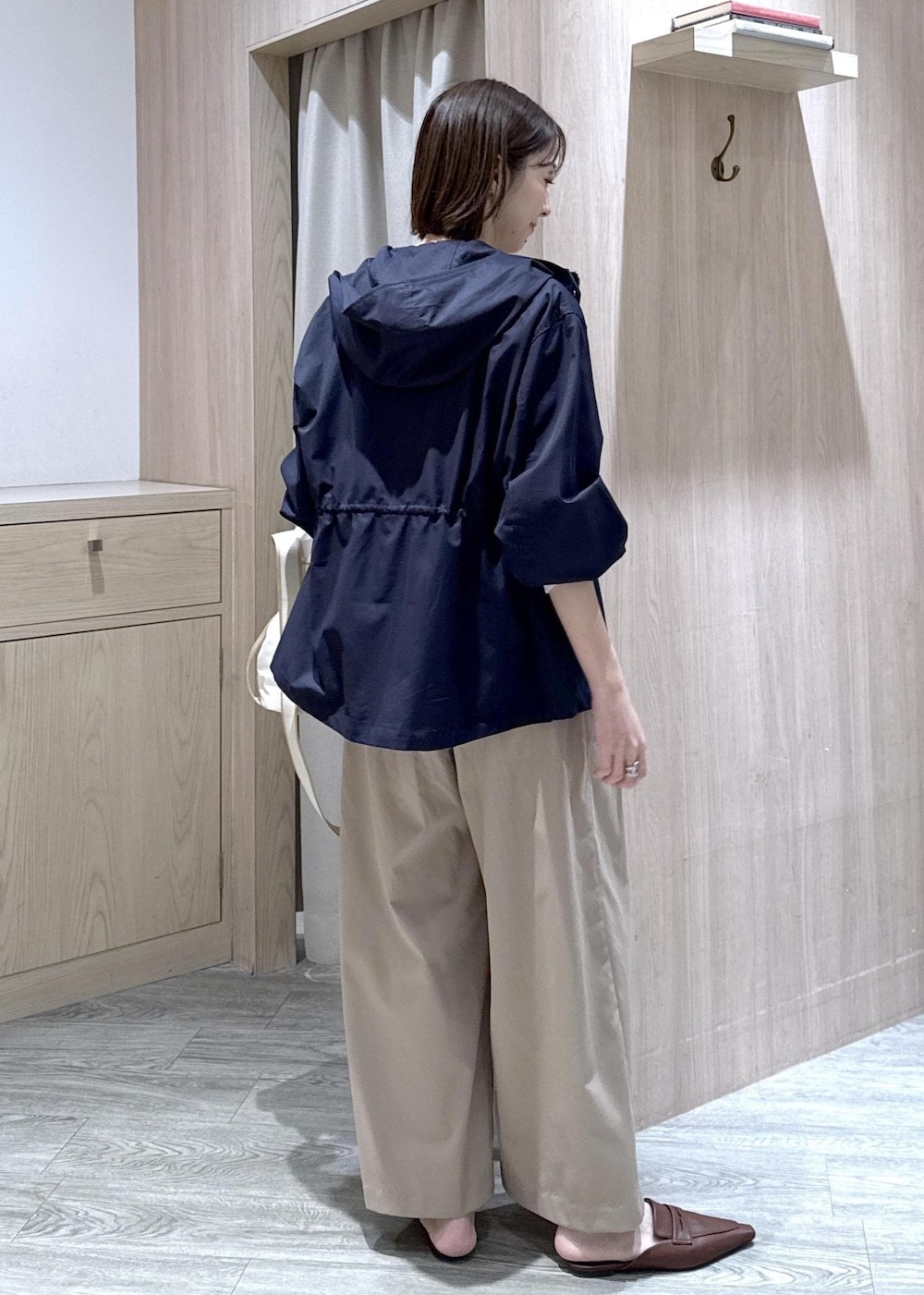 ホワイト系のカーディガン/ボレロ、ホワイト系のトートバッグ、ブルー系のナイロンジャケットを着用したレディースの春コーディネートの2枚目の写真