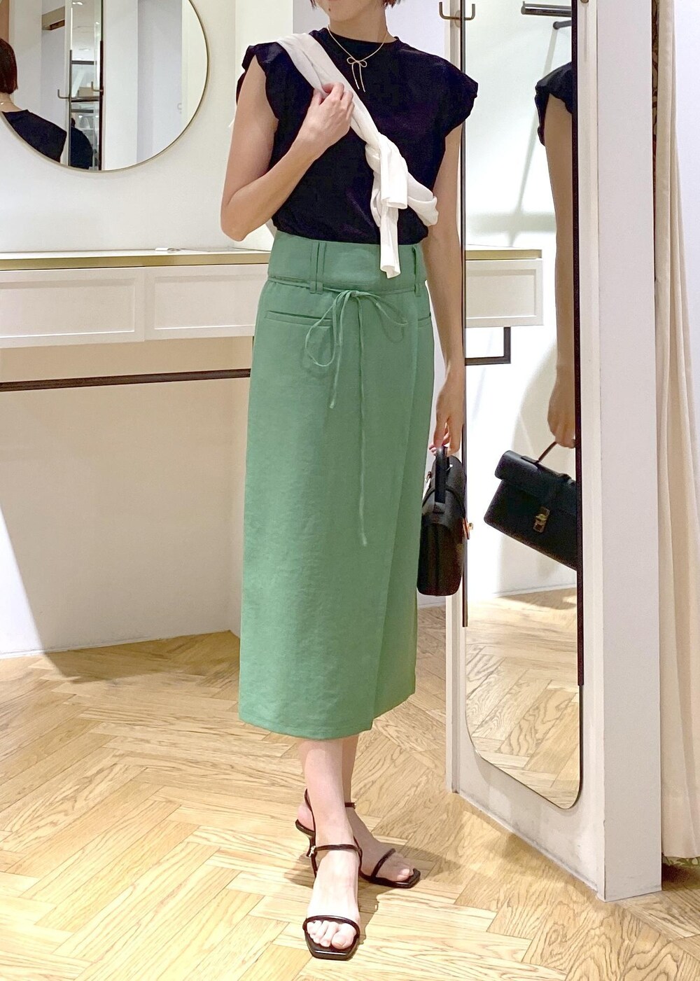 ブラック系のショルダーバッグ、ブラック系のサンダル、ホワイト系のカーディガン/ボレロを着用したレディースの夏コーディネートの3枚目の写真