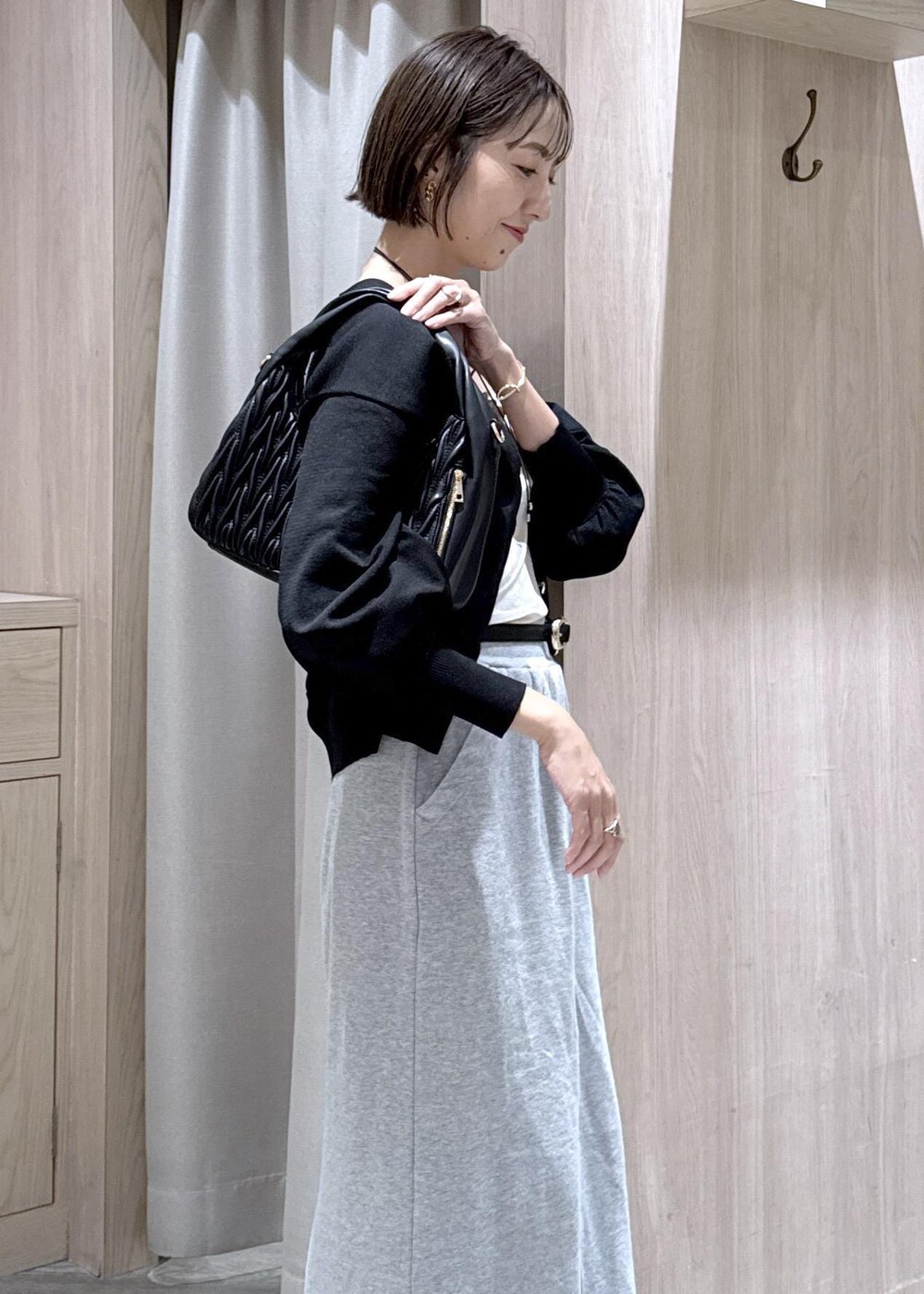 グレー系のスカート、ホワイト系のキャミソール、ブラック系のカーディガン/ボレロを着用したレディースの秋コーディネートの7枚目の写真