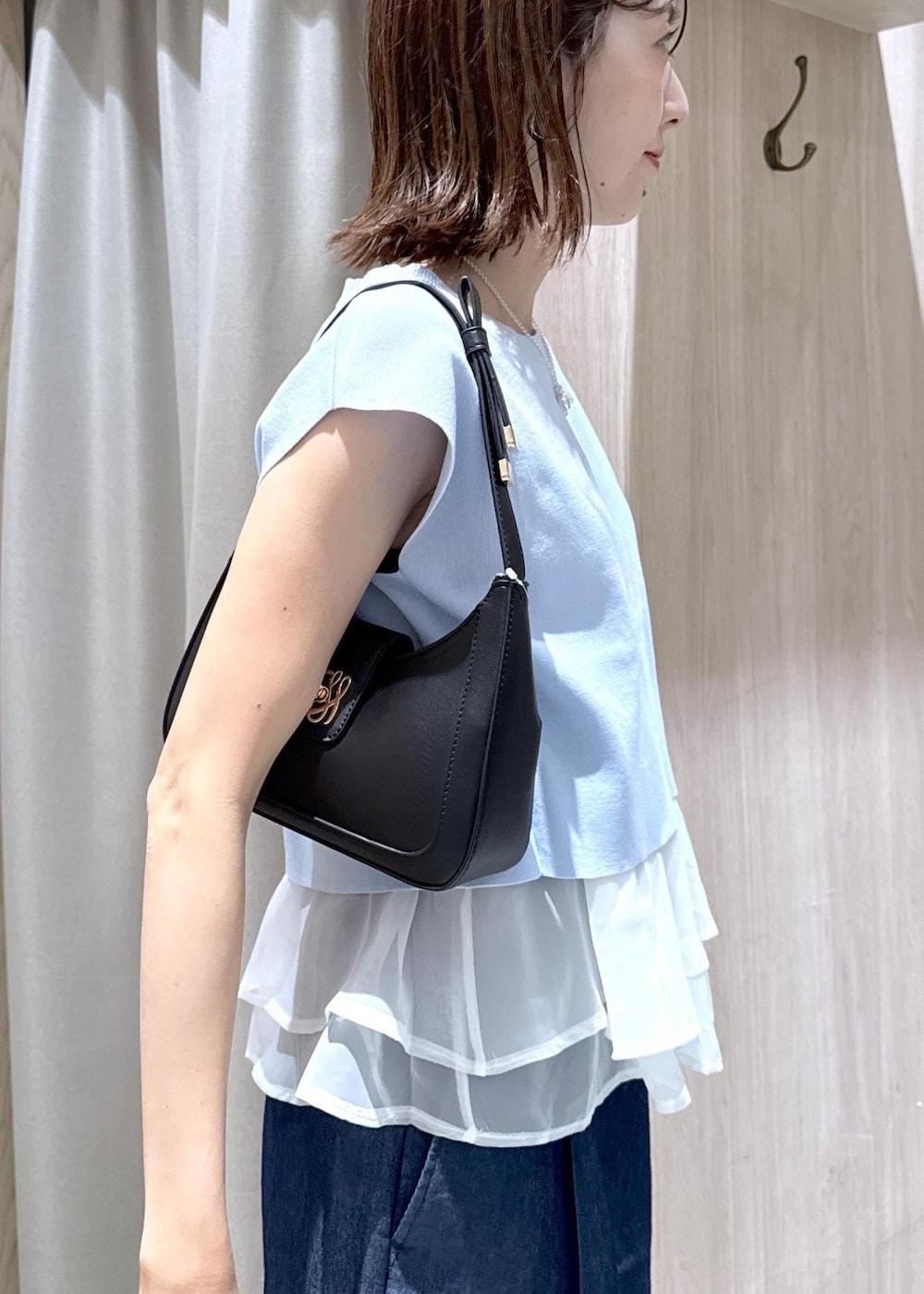 ブラック系のショルダーバッグ、ブラック系のパンプス、ブルー系のデニムパンツを着用したレディースの夏コーディネートの9枚目の写真