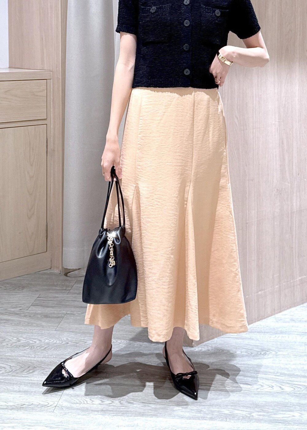 ブラック系のパンプス、オレンジ系のスカート、ブラック系のハンドバッグを着用したレディースの春コーディネートの7枚目の写真