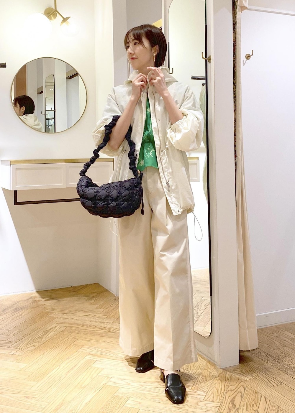 ホワイト系のスラックス、ホワイト系のマウンテンパーカー、ブラック系のサンダルを着用したレディースの春コーディネートの4枚目の写真