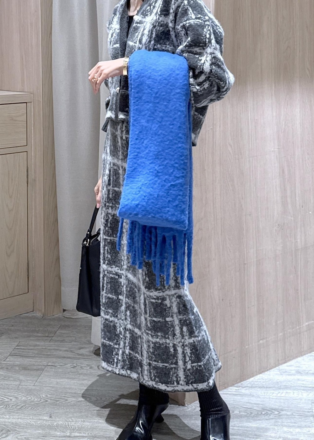 グレー系のスカート、グレー系のカーディガン/ボレロ、ブラック系のショルダーバッグを着用したレディースの冬コーディネートの3枚目の写真