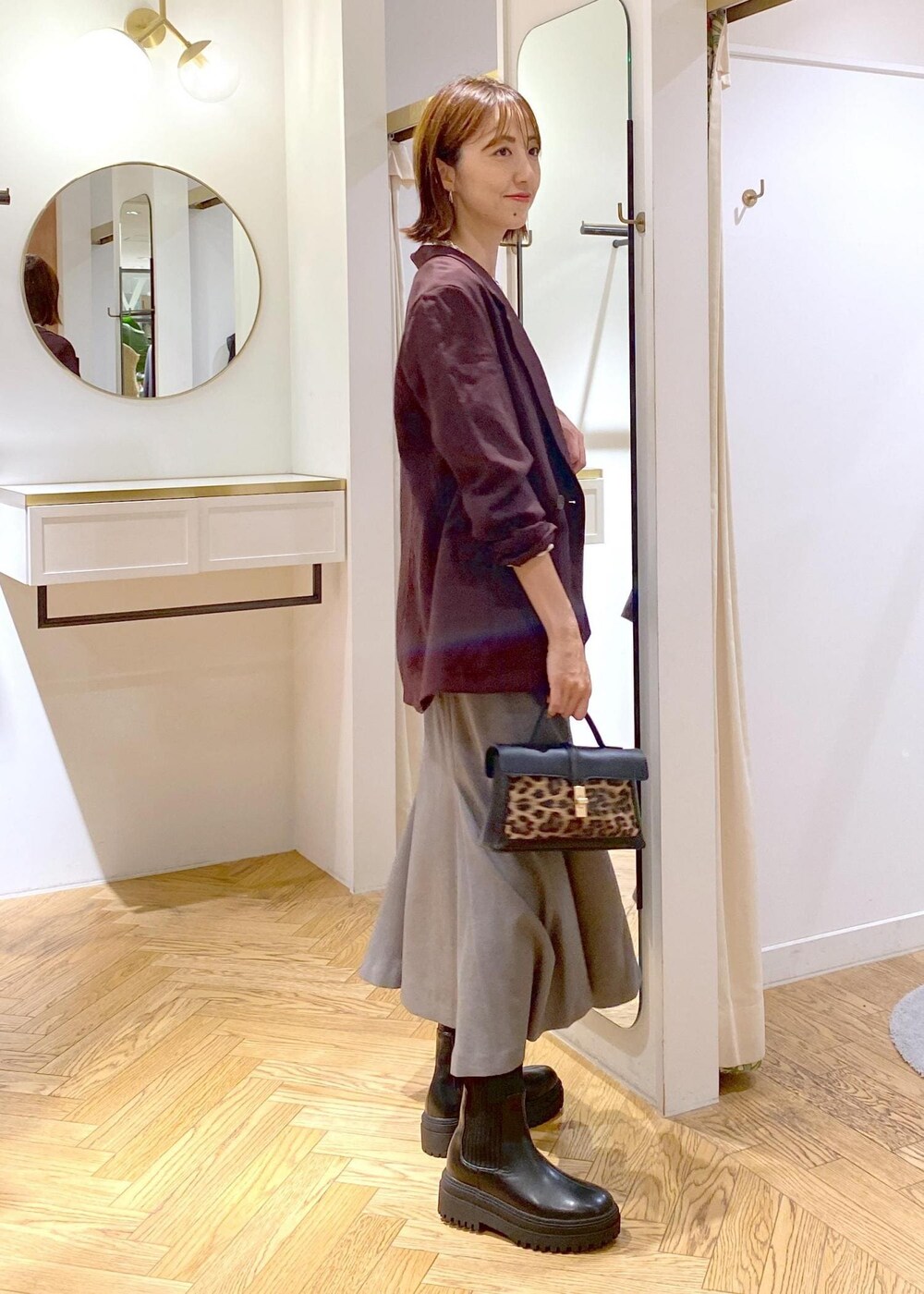 ブラック系のキャミソール、その他のショルダーバッグ、ブラック系のブーツを着用したレディースの秋コーディネートの2枚目の写真