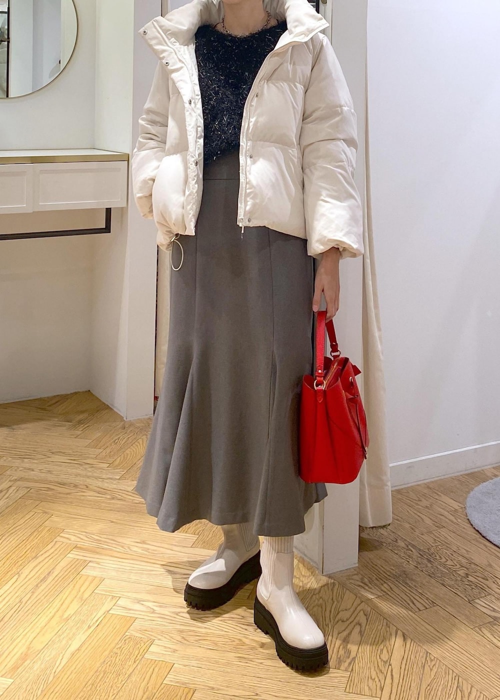 ホワイト系のブーツ、グレー系のスカート、ホワイト系のダウンジャケット/コートを着用したレディースの冬コーディネートの4枚目の写真