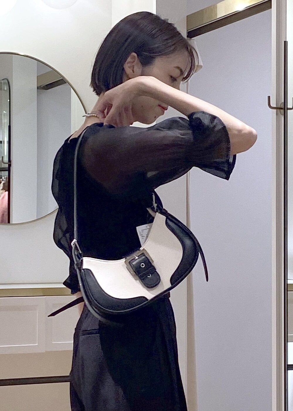 ブラック系のパンプス、ブラック系のショルダーバッグ、ブラック系のスラックスを着用したレディースの夏コーディネートの6枚目の写真