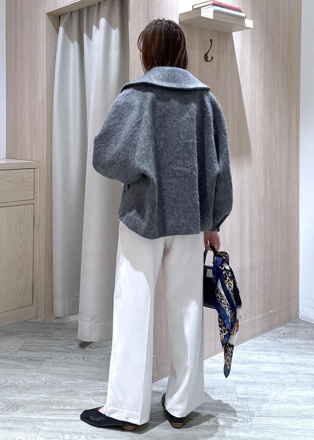 ブラック系のニット/セーター、グレー系のブルゾン、ブラック系のハンドバッグを着用したレディースの冬コーディネートの9枚目の写真