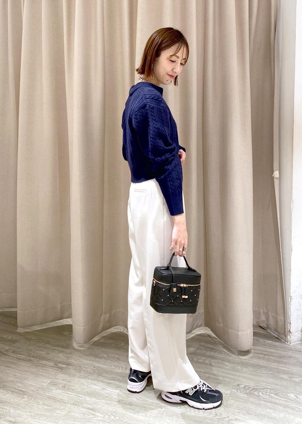 ブラック系のキャミソール、ブラック系のハンドバッグ、ホワイト系のスラックスを着用したレディースの冬コーディネートの3枚目の写真